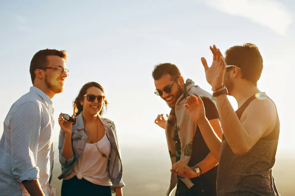 three men and one woman laughing during daytime Friends enjoying a shared moment, reflecting lifestyle and well-being